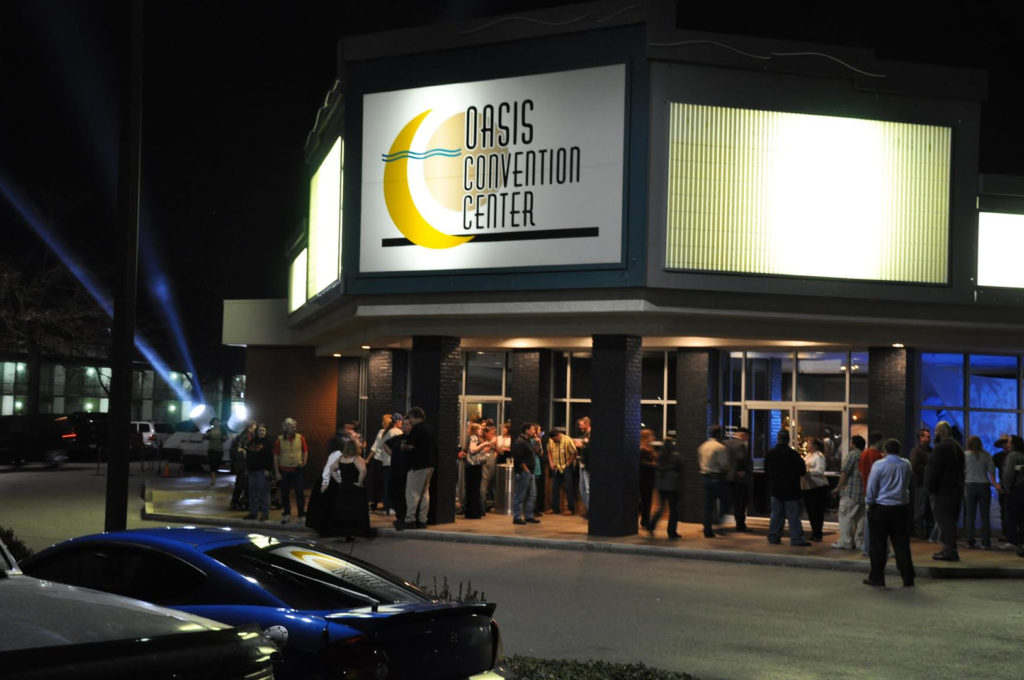 People outside Oasis Convention Center at night.